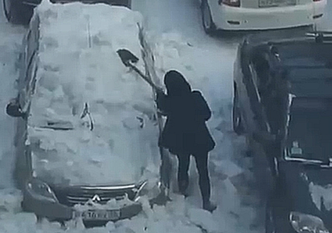 Девушка чистит снег с автомобиля железной лопатой 